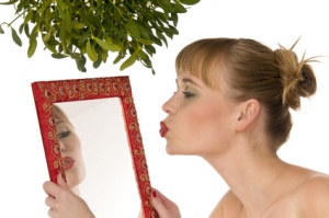 Naked model kissing herself in a mirror under mistletoe isolated on white